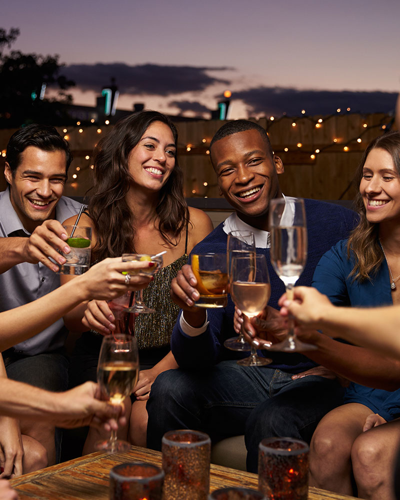 Group of friends hanging drinks on rooftop